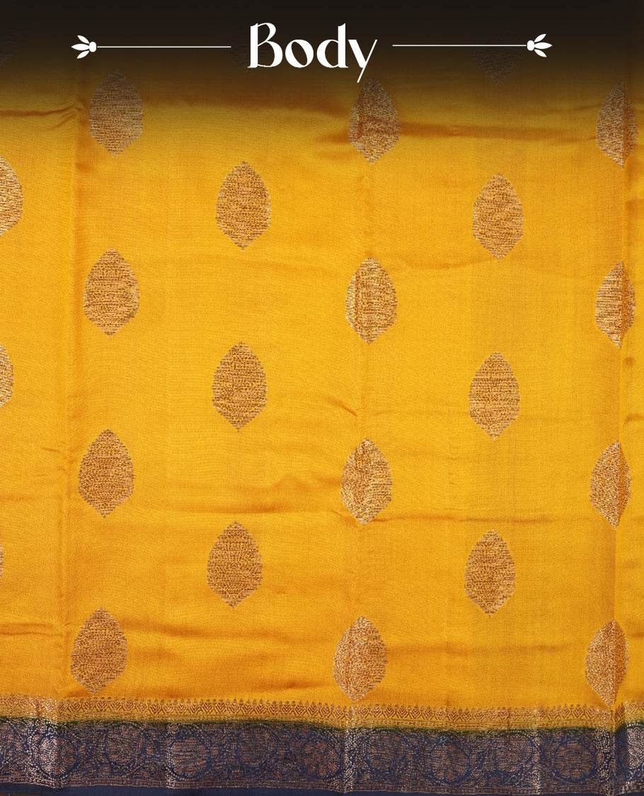 Golden Yellow Colour Banaras Soft Silk Saree with Gold Zari Oval Leaf Buttas, Intricate Multi-Layered Floral Border, Grand Pallu with Ornate Brocade Motifs in Navy Blue and Gold Tones, and Matching Blouse.