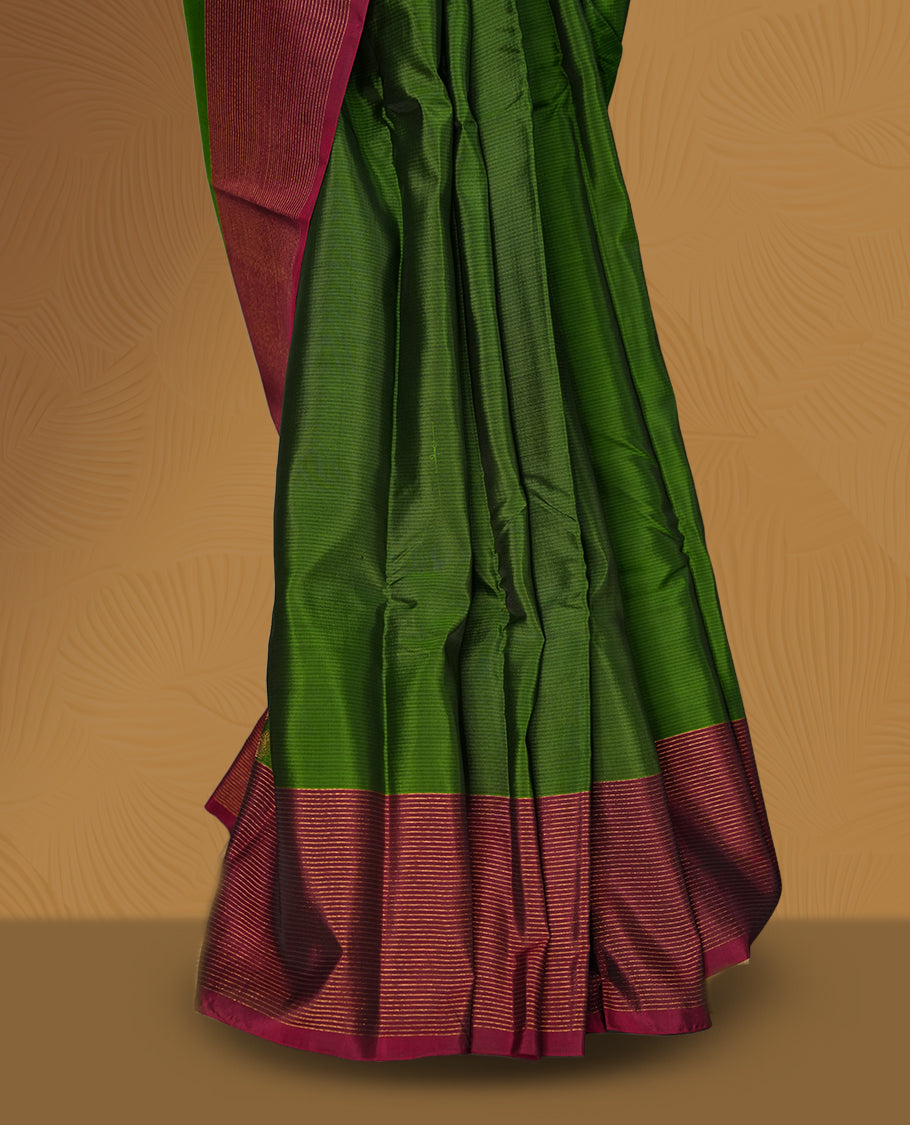 Green colour soft silk saree adorned with minimal golden motifs, paired with a contrasting maroon border and pallu featuring elegant zari patterns & Comes with a matching blouse.