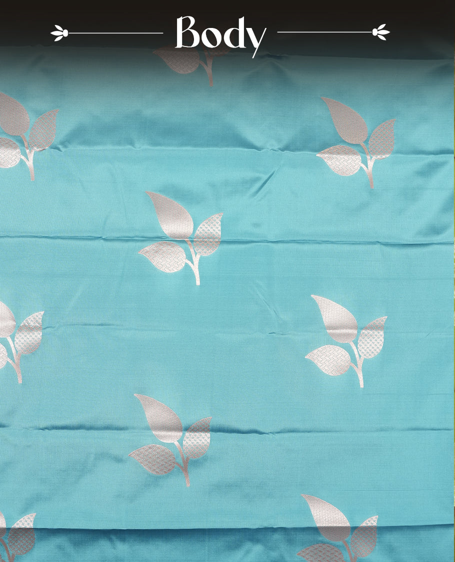 Sky blue colour semi silk saree adorned with elegant floral motifs on the body, complemented by a shimmering golden zari-woven pallu and border, and paired with a matching blouse