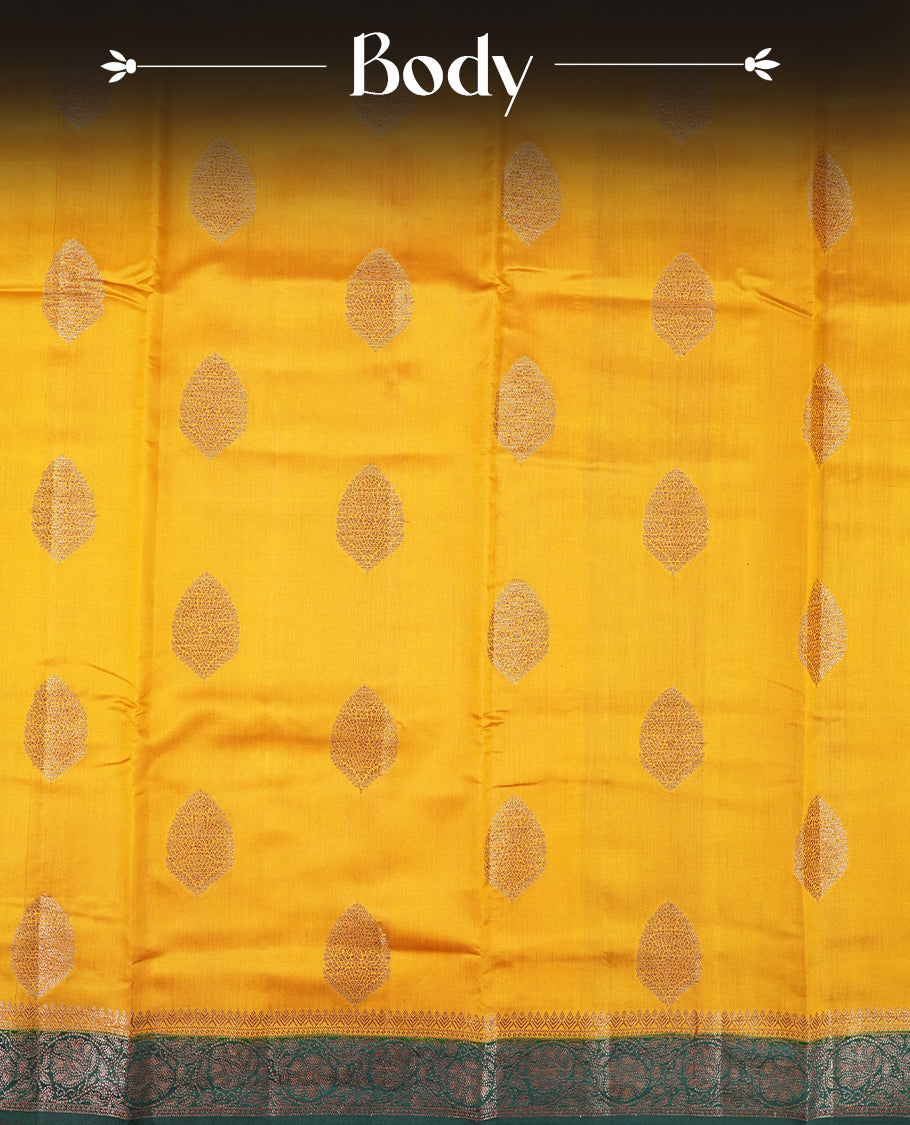 Mustard Yellow Colour Banaras Soft Silk Saree with Gold Zari Oval Buttas, Intricate Multi-Layered Floral Border, Grand Pallu with Ornate Lotus and Vine Motifs in Teal and Gold Tones, and Matching Teal Blouse.