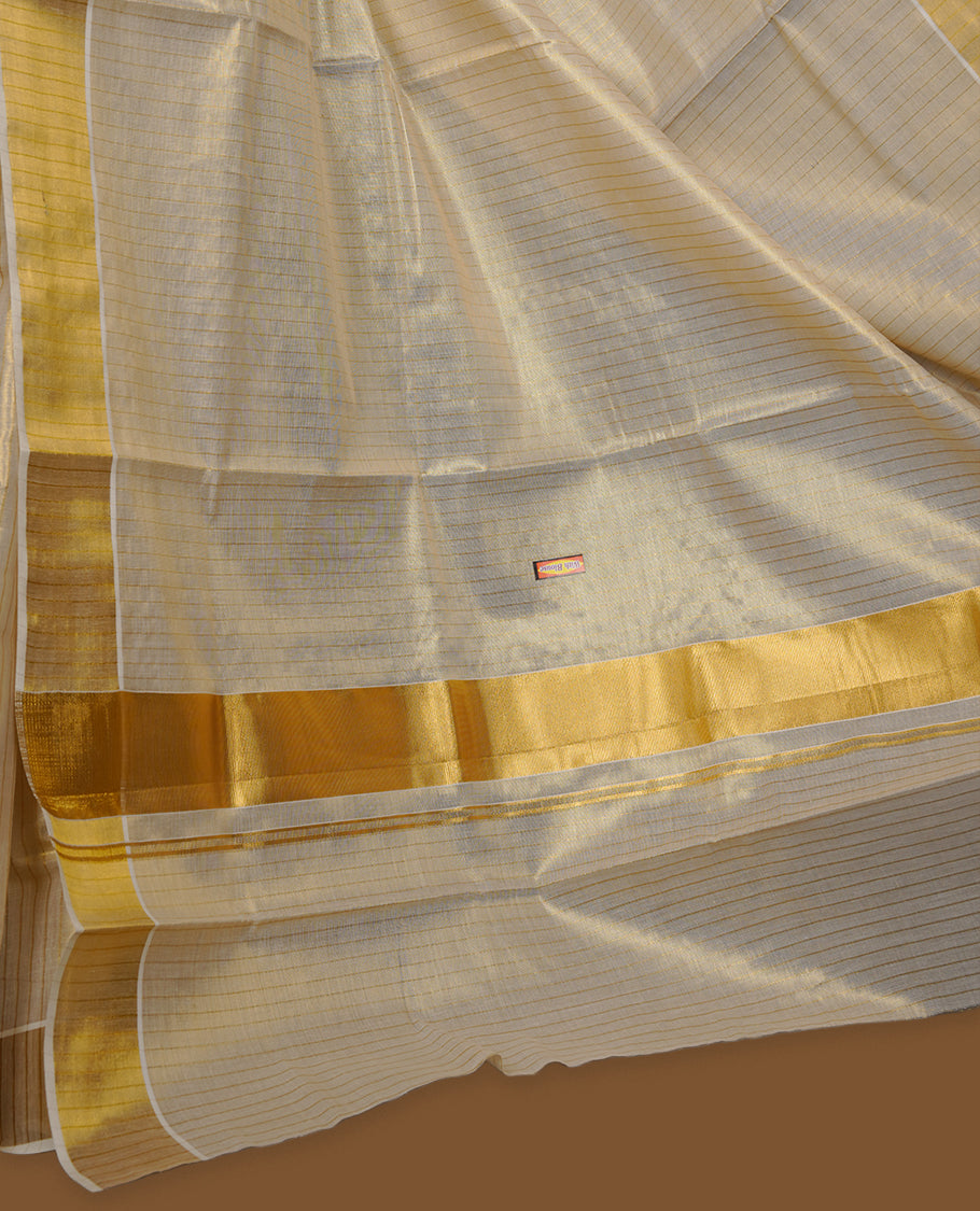 Off-white colour tissue Kerala saree with a timeless gold kasavu border, featuring a subtle striped weave across the body and pallu, paired with a matching blouse.