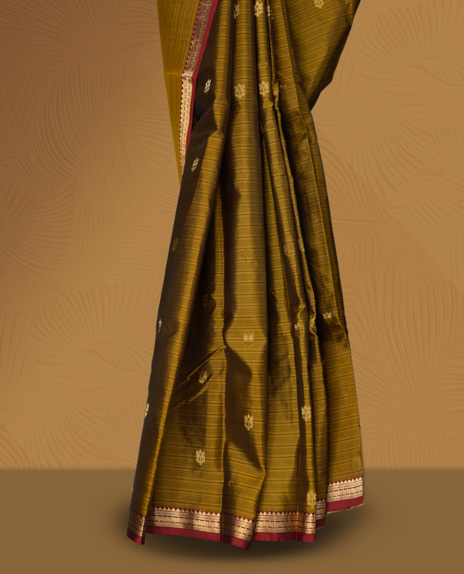 Dusty mustard yellow soft silk saree enhanced with delicate zari buttas, paired with a striking rust orange zari border and elegant pallu & Comes with a matching blouse.