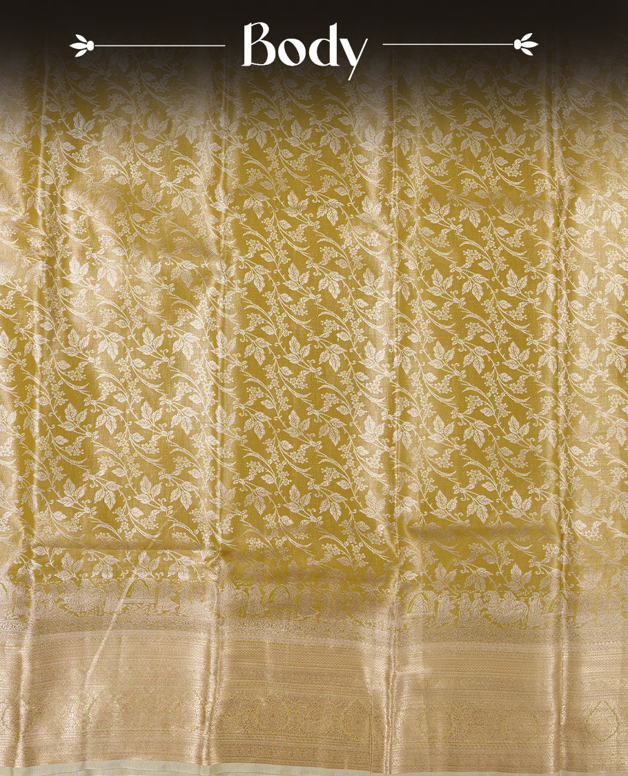 Light olive-gold antique zari tissue brocade saree with delicate woven floral motifs, a traditional gold zari border and pallu, paired with a matching blouse.