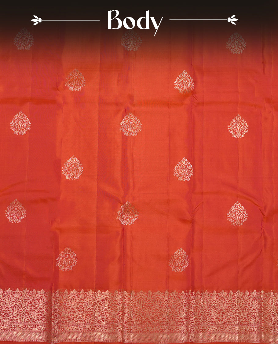 Burnt orange colour Vasundhara silk saree adorned with all-over gold motifs on the body, complemented by a self colour with gold tarditional border and paired with a matching blouse piece.
