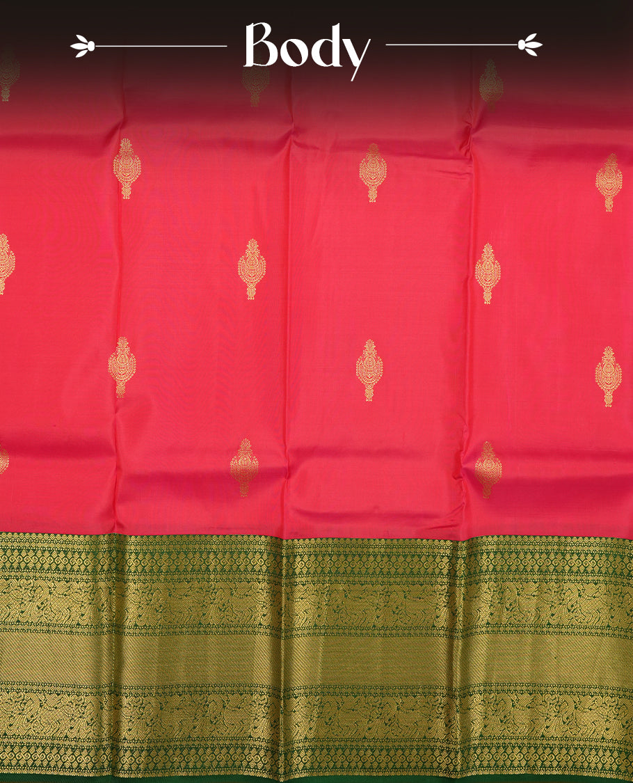 Rani pink colour Vasundhara silk saree adorned with all-over gold motifs on the body, complemented by a contrast green with gold tarditional border and paired with a matching blouse piece.