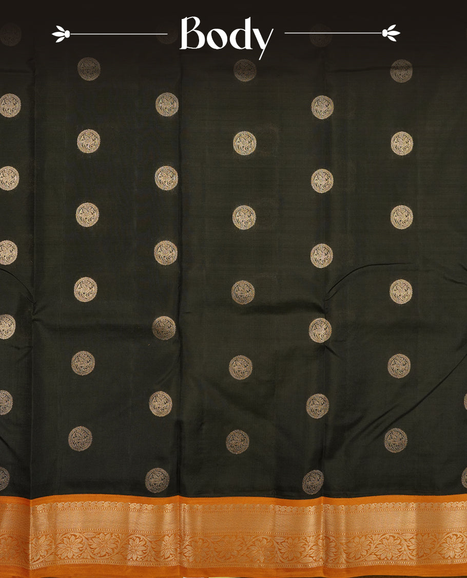 Black colour Vasundhara silk saree adorned with all-over gold chakkaram motifs on the body, complemented by a contrast turmeric colour with gold flower kodi motifs border and paired with a matching blouse piece.