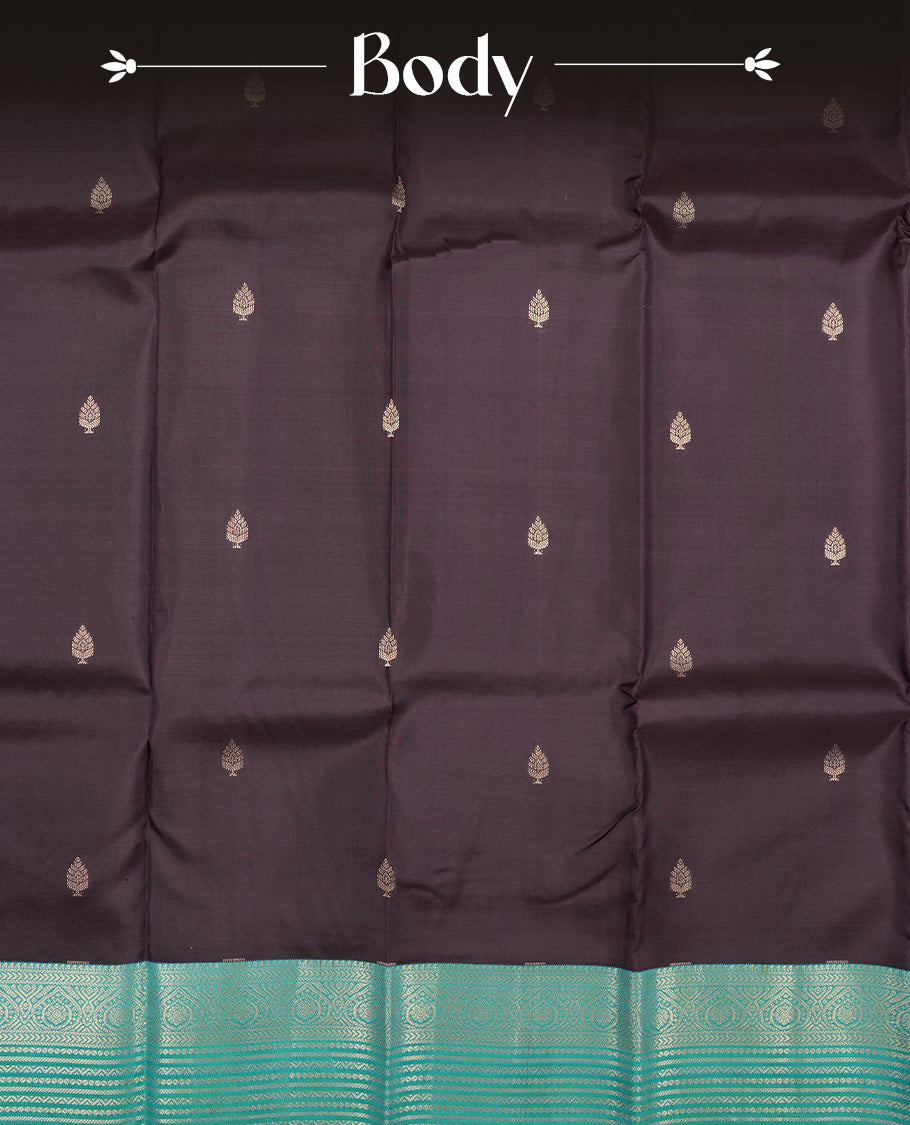 Dark purple colour Vasundhara silk saree adorned with all-over gold motifs on the body, complemented by a contrast green with gold tarditional border and paired with a matching blouse piece.