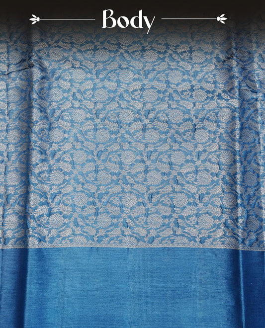 Teal Blue  colour Pure tusser silk saree featuring Silver  Zari floral Kodi Work On Body , A Plain  border & Grand  pallu ,Paired With  a matching blouse piece.