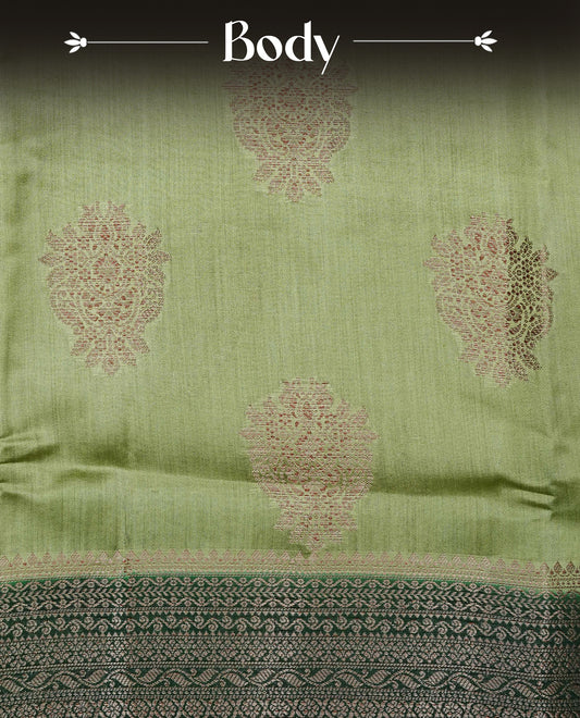 Pastel Pistachio Green Colour Tussar Silk saree with elegant antique zari floral motifs On Body, a contrasting dark green zari border, a rich zari pallu, and a matching blouse piece.
