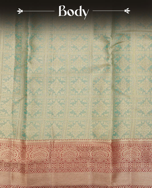 Green colour Semi Tissue Silk Saree featuring gold zari Works on the body, complemented by an intricately woven gold zari pallu, a rich Maroon border with gold zari work and paired with a matching plain blouse piece.