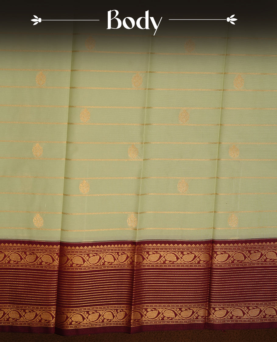 Mint green coloured soft silk saree featuring gold zari stripes and motifs across the body, enhanced with a contrast Maroon border and pallu, paired with a matching contrast blouse piece.