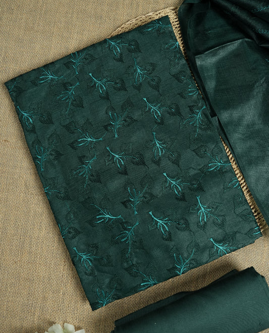Deep jungle green colour tussar suit material featuring elegant floral thread embroidery on the body, paired with a soft dupatta adorned with matching embroidered motifs and tassel edges, along with a plain bottom piece.