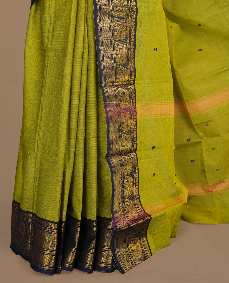 Olive green colour chettinad cotton saree featuring small buttas on body, complemented by contrast blue colour with gold zari border, paired with matching blouse piece.