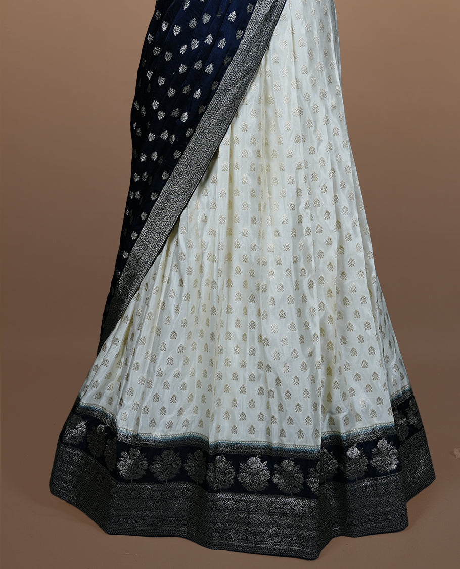 Off white semi banaras semi stitched dhavani set featuring gold zari motifs and contrast Teal colour and traditional border, unstitched gold zari blouse piece and matching Duptta.
