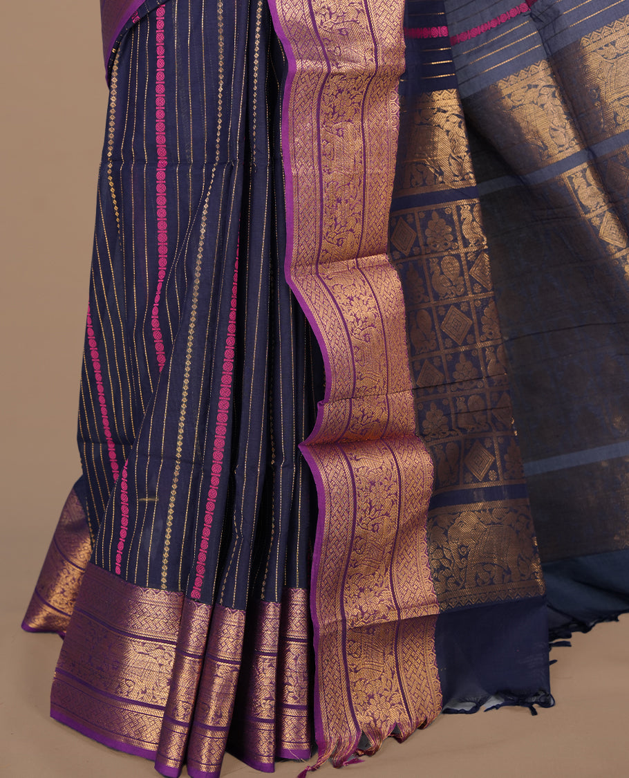 Navy blue colour chettinad saree featuring gold zari stripes on body, complemented by contrast Purple colour with traditional border, paired with matching blouse piece.