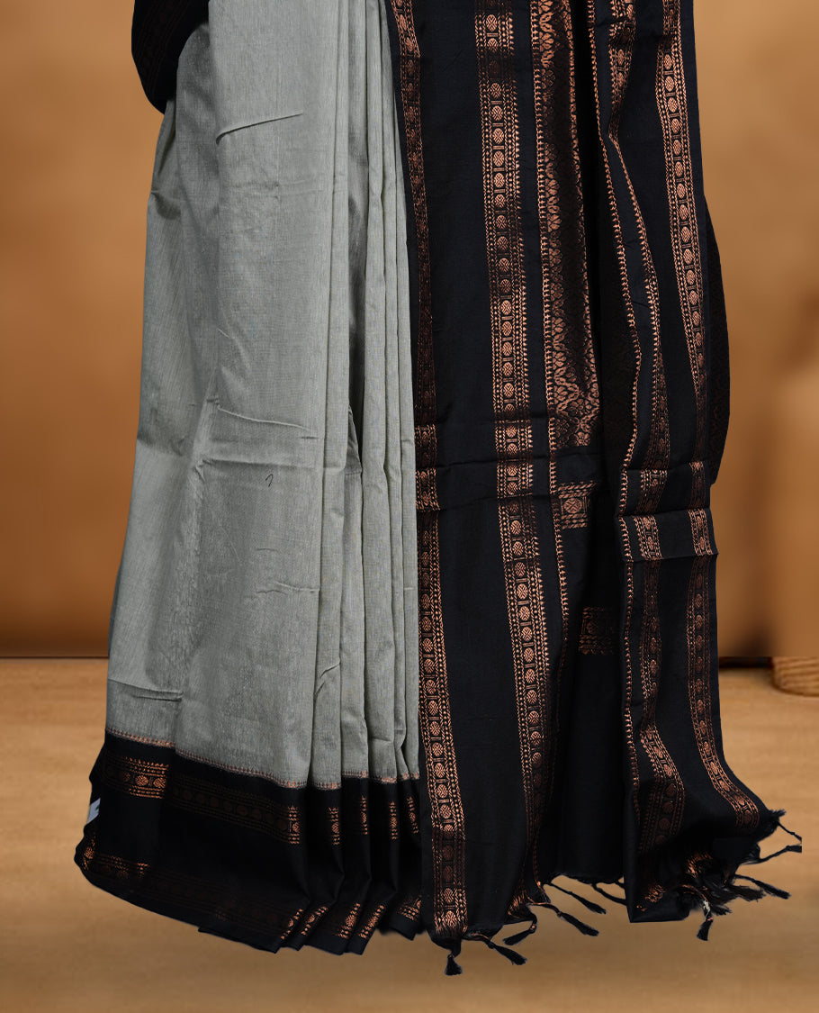 Grey colour Kalyani cotton saree featuring a plain elegant body, complemented by a black zari border and traditional woven pallu, paired with a matching blouse.