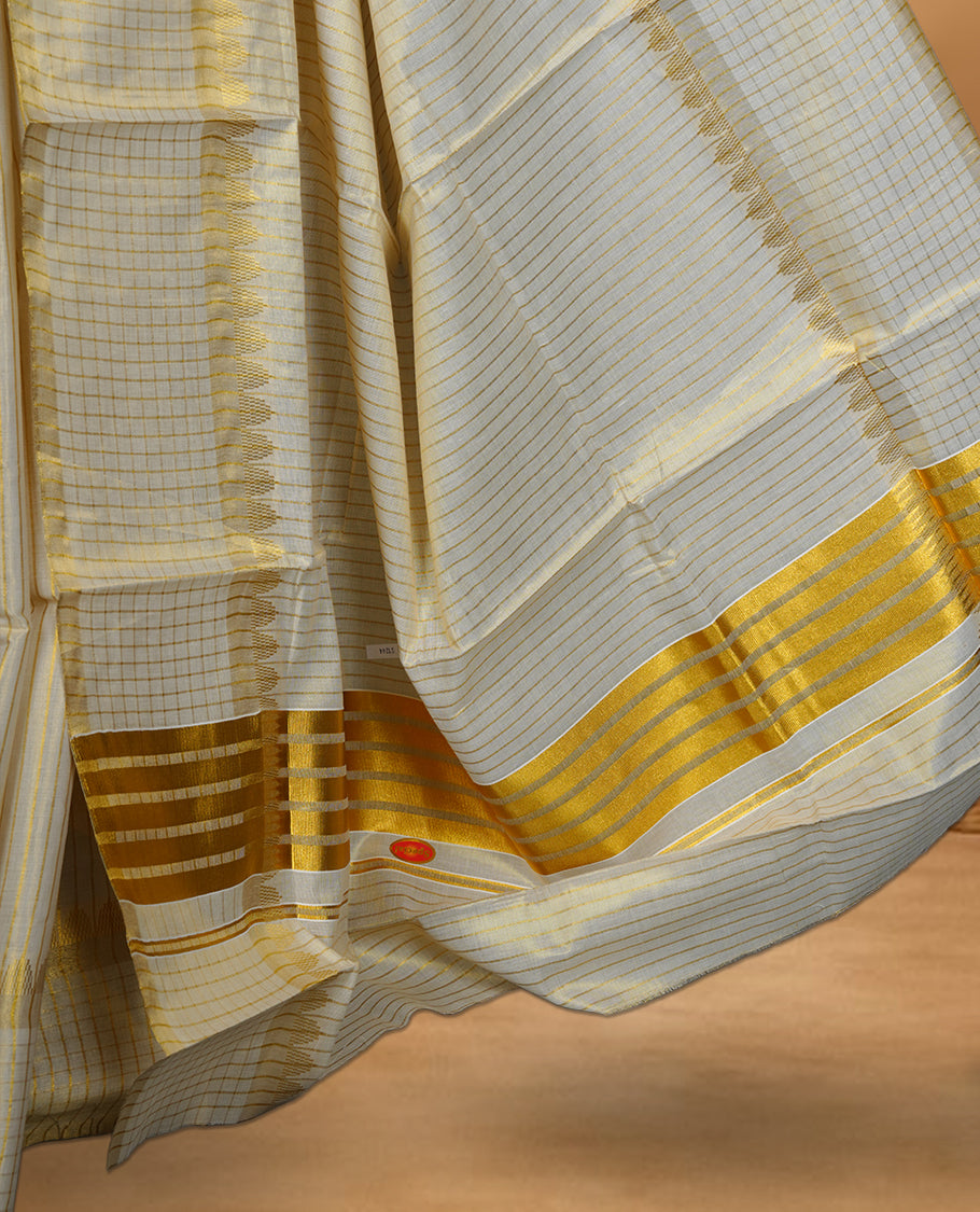 Off white colour Tissue Kerala saree featuring a fine striped and checked body, complemented by a classic golden zari border and traditional pallu design, paired with a matching blouse.