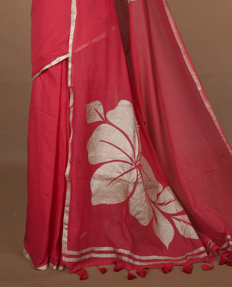 Red coloured mul cotton saree featuring bold gold-tone floral motifs across the body, designed without a border and comes without a blouse piece.