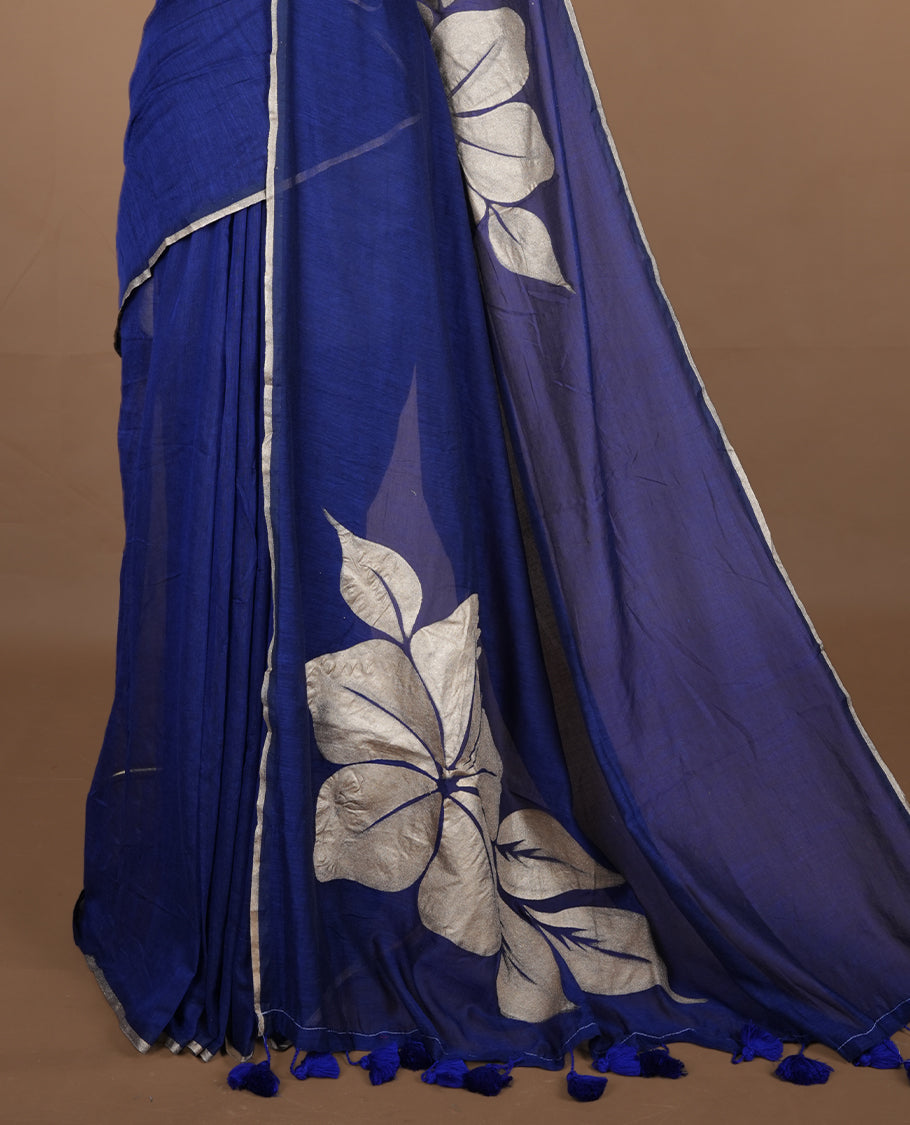 Blue coloured mul cotton saree featuring bold gold-tone floral motifs across the body, designed without a border and comes without a blouse piece.