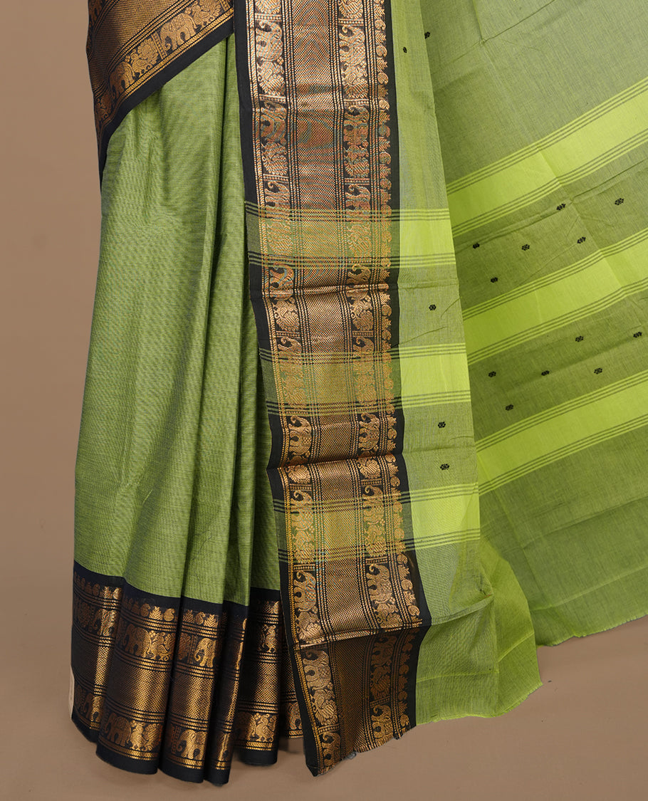 Green colour chettinad saree featuring gold zari motifs on body, complemented by contrast black colour with traditional border, paired with matching blouse piece.