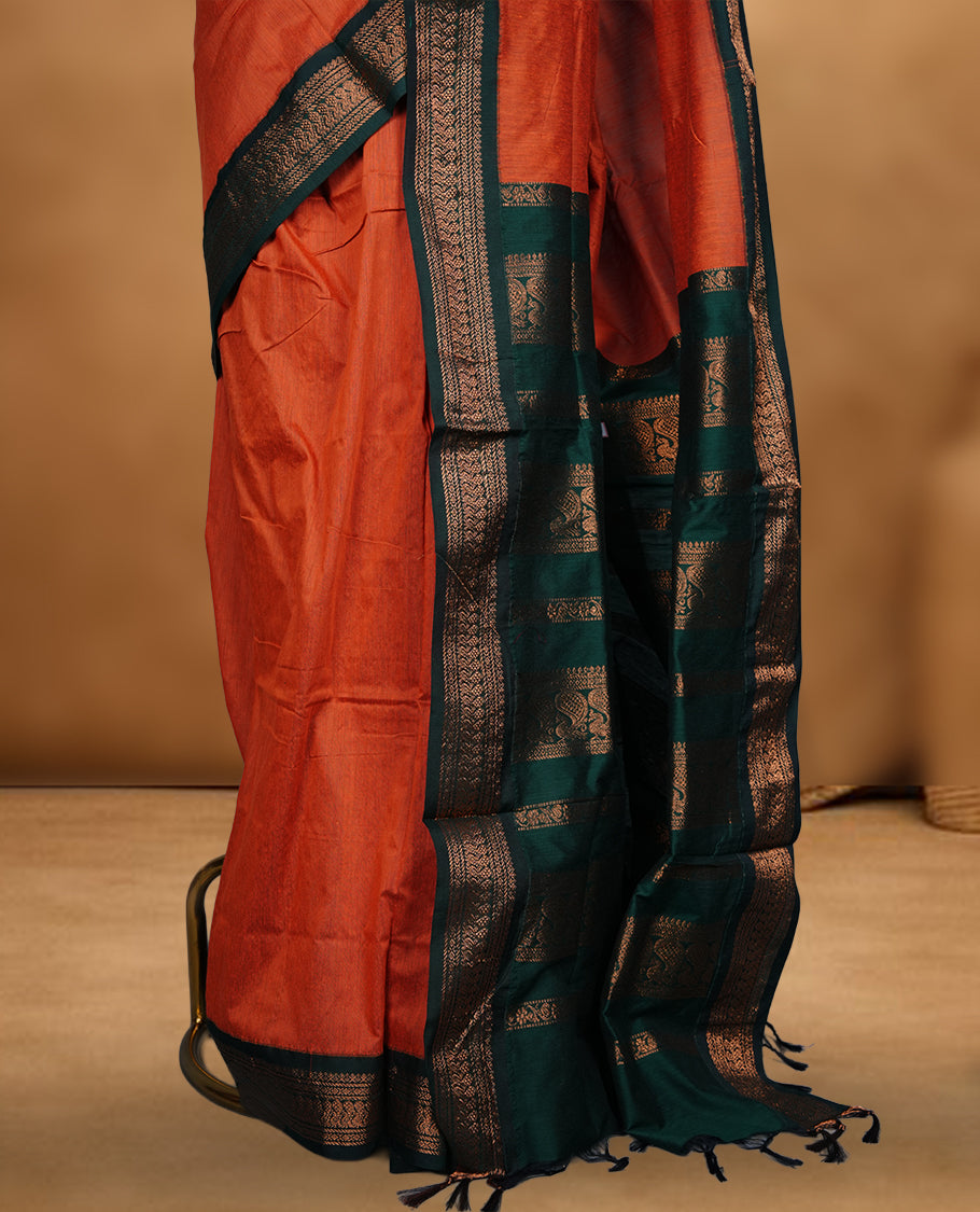 Rust orange colour Kalyani cotton saree featuring a plain elegant body, complemented by a rich green zari border and traditional woven pallu, paired with a matching blouse.