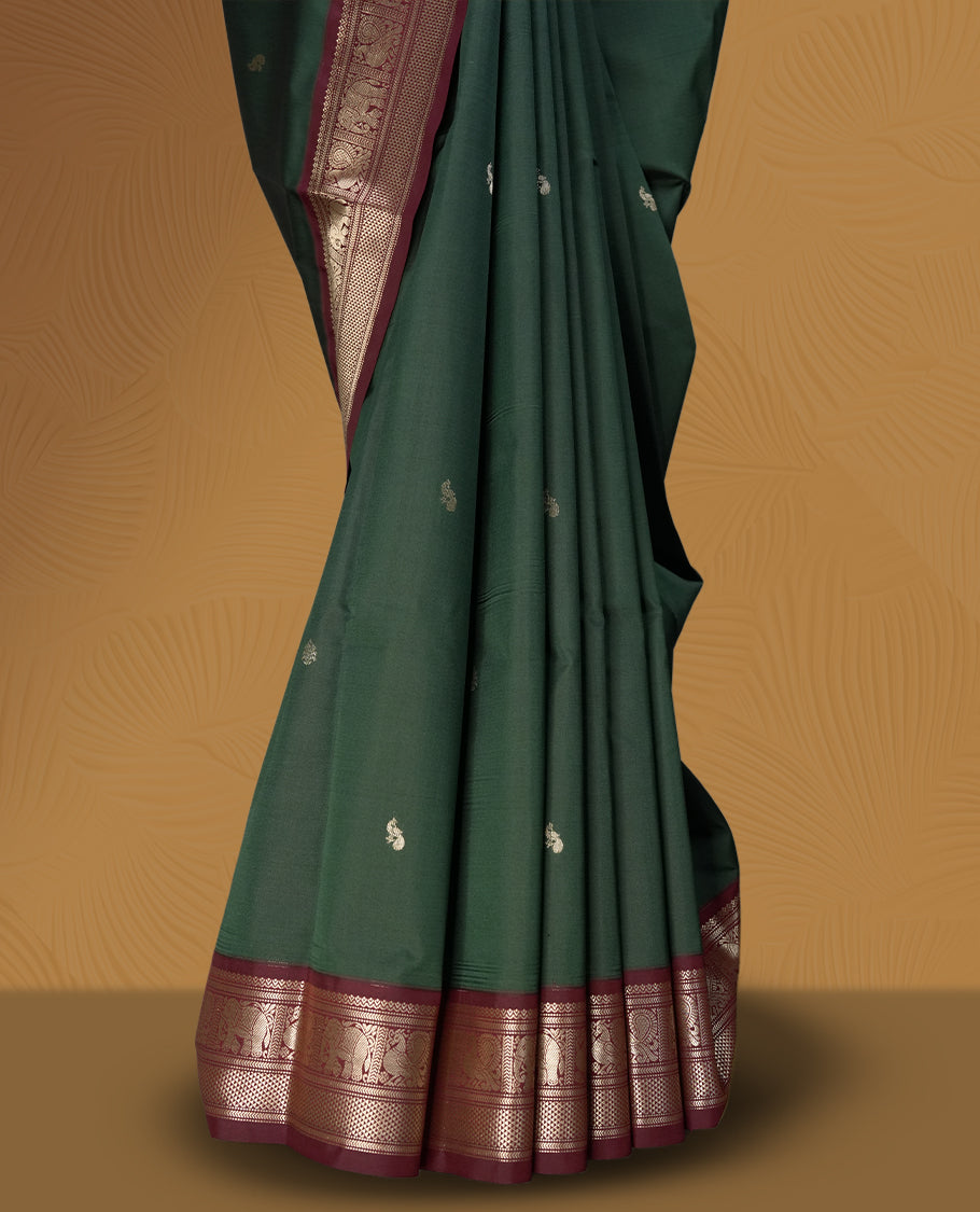 Dark green colour soft silk saree with silver buttas, enhanced by a vibrant maroon zari border and pallu, paired with a matching blouse.