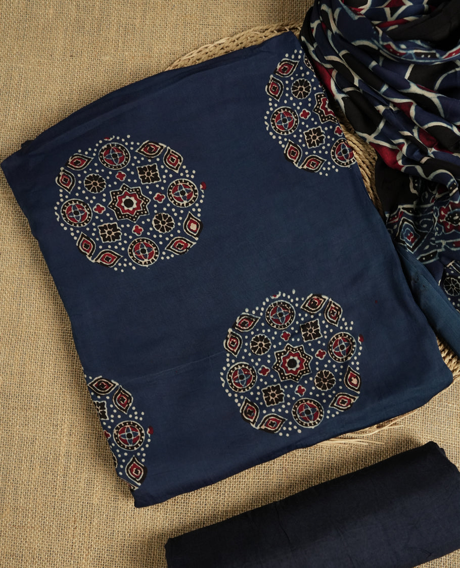 Navy blue suit material featuring intricate Ajrak inspired prints in maroon, blue, and off white & Includes a beautifully patterned dupatta and matching plain bottom.