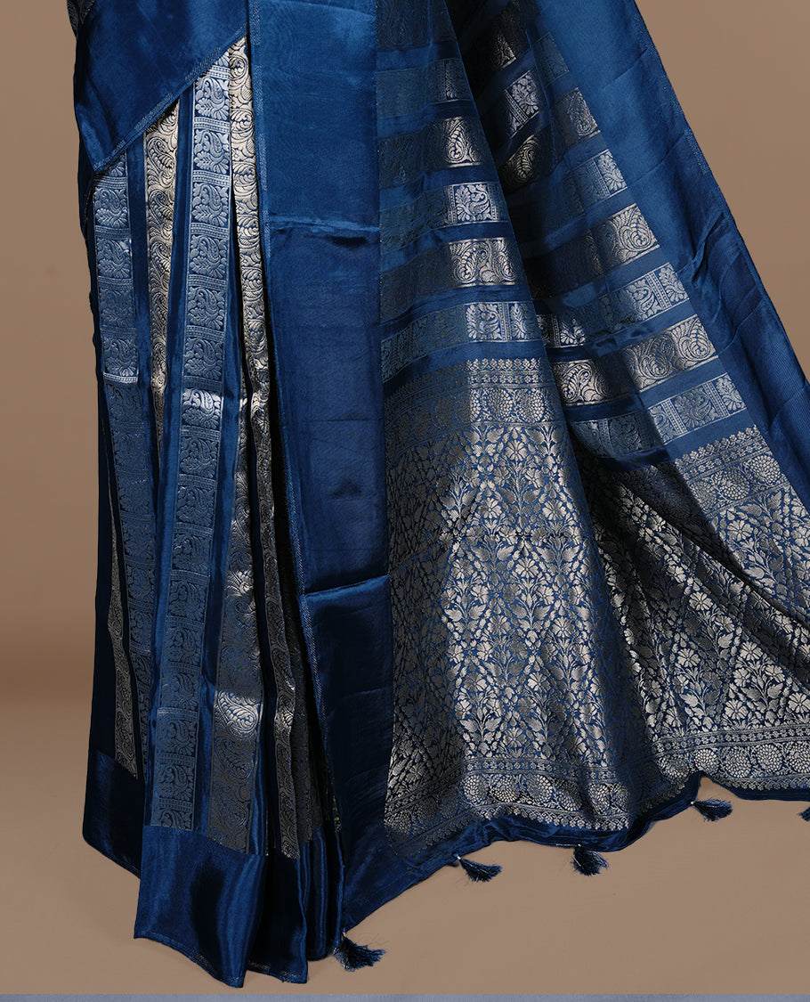 Teal colour banaras crepe saree featuring gold & silver zari design stripes on body, complemented by self colour border, paired with matching blouse piece.