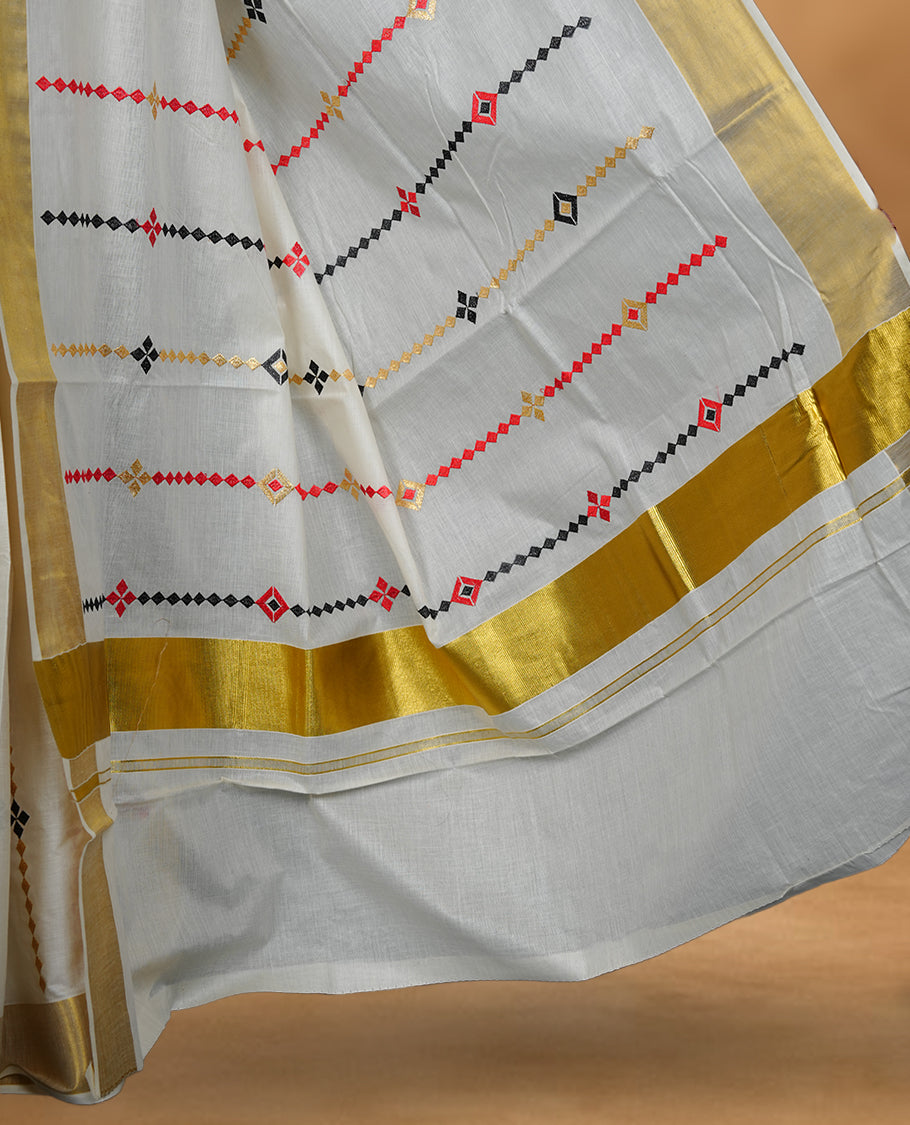 Off white Kerala saree featuring red and black geometric motifs, complemented by a classic golden zari border and traditional pallu, paired with a matching blouse.