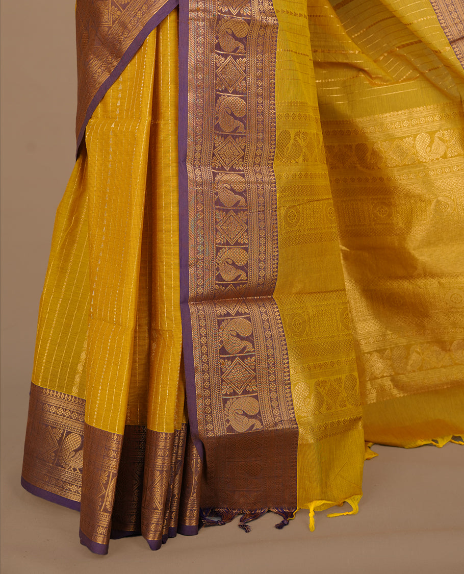 Olive yellow colour chettinad saree featuring gold zari motifs on body, complemented by contrast purple colour with traditional border, paired with matching blouse piece.