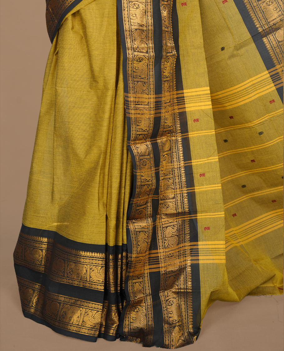 Olive colour chettinad saree featuring gold zari motifs on body, complemented by contrast black colour with traditional border, paired with matching blouse piece.