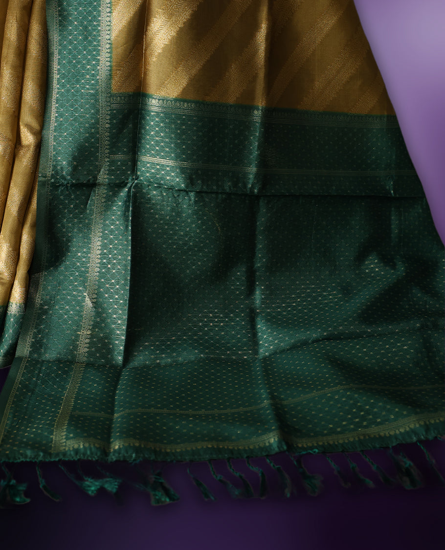 Golden saree featuring subtle self striped woven patterns on the body, enhanced with a green geometric border, complemented by a rich zari pallu with tassels, and paired with a matching blouse for a traditional elegant look.