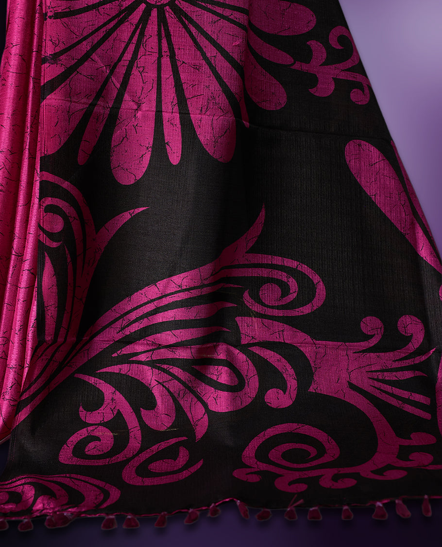 Black and Pink colour semi modal saree featuring bold floral and abstract motifs across the body, complemented by a striking patterned pallu, finished with tassel details and paired with a matching blouse.