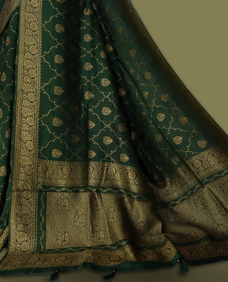 Dark green colour semi Banarasi Tussar Georgette saree with gold zari motifs on the body, a grand woven golden pallu, and ornate zari border. Includes a matching blouse piece for a complete look.