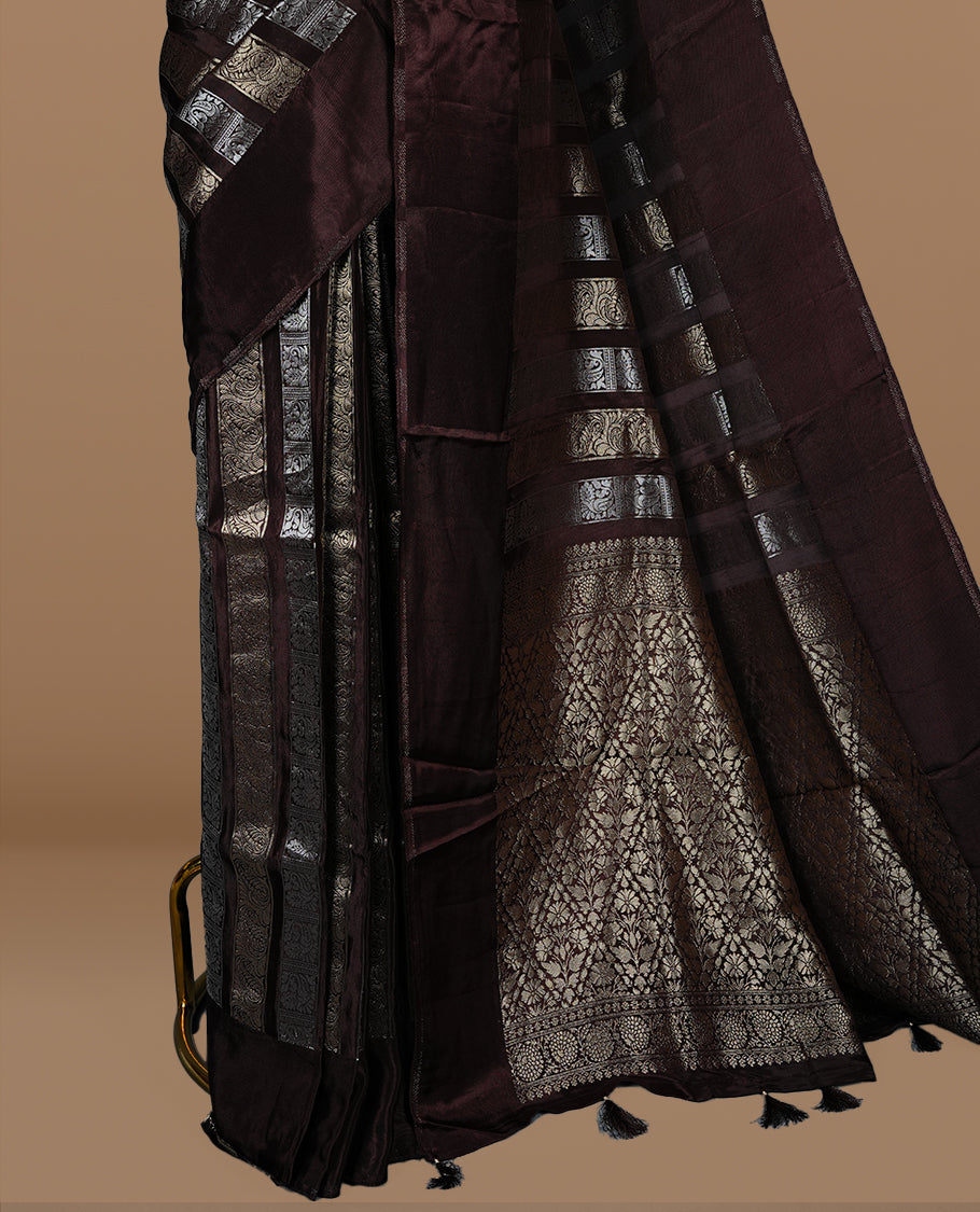 Chocolate colour banaras crepe saree featuring gold & silver zari design stripes on body, complemented by self colour border, paired with matching blouse piece.