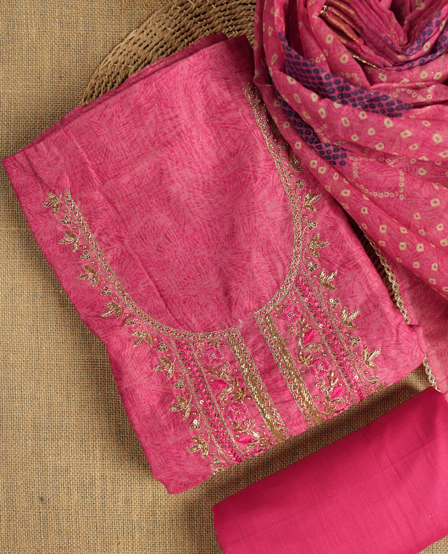 Dark pink colour suit material adorned with pearls, sequins and cut beads embroidery work on the neckline, exuding a graceful charm & Paired with a floral printed dupatta and a matching plain bottom.