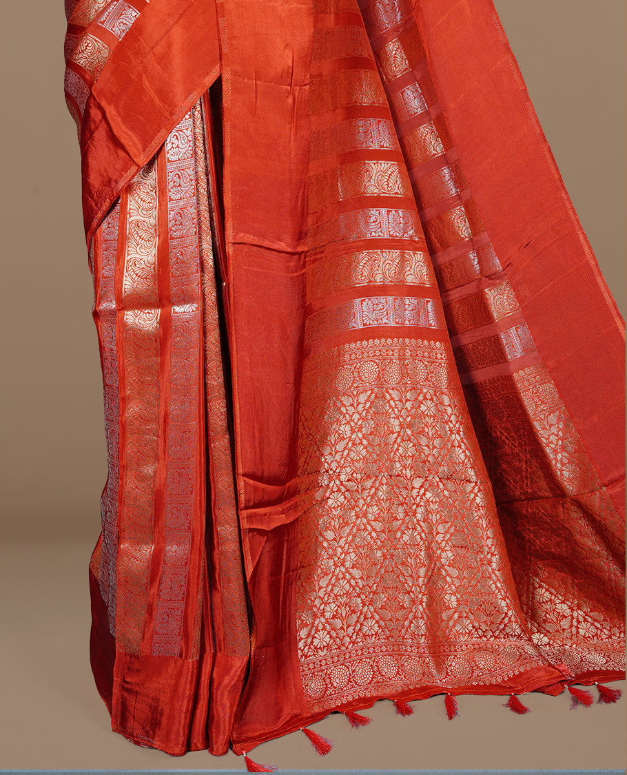Brick red colour banaras crepe saree featuring gold & silver zari design stripes on body, complemented by self colour border, paired with matching blouse piece.