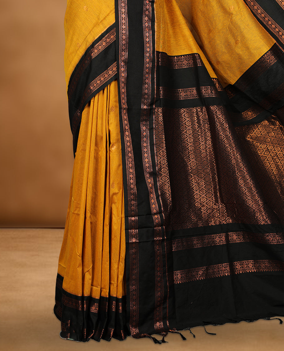 Mustard colour kalyani cotton saree featuring Antique zari motifs on body, contrast Black colour border with floral and chakra antique zari pattern, paired with matching blouse piece.