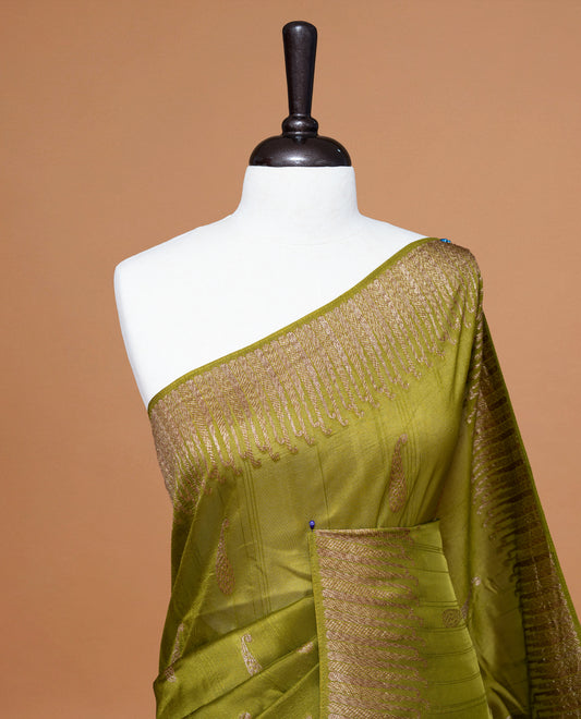 Olive colour Semi Banaras Tussar Georgette Featuring Gold zari Leaf pattern on body, Finished with Gold zari border and paired with matching blouse piece.