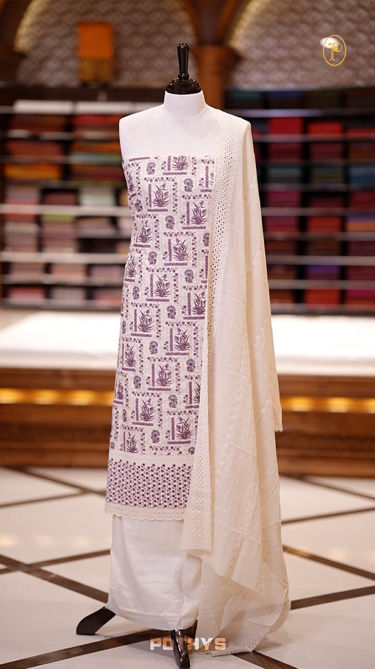 Beige & violet Hakoba cotton churidhar material with violet & green floral top, lace border under the top and sides & Cotton dupatta with lace detailing & plain bottom for elegant wear.