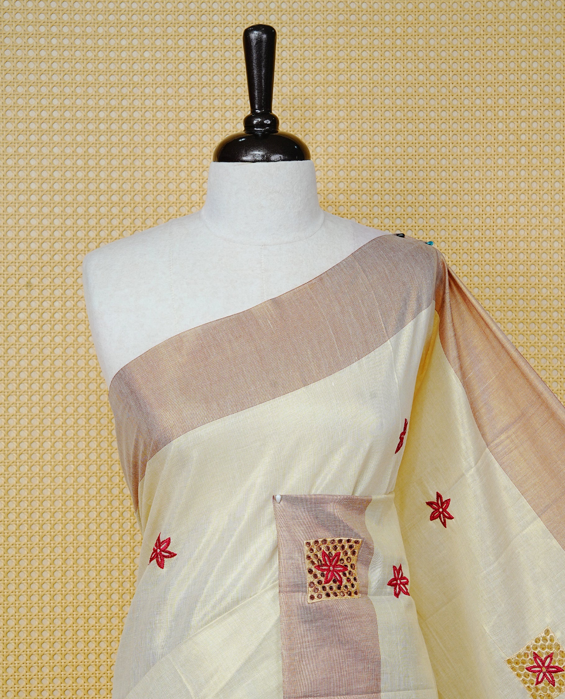 Cream Colour Tissue Kerala Saree Featuring Delicate Brick Red Floral Embroidery Work Across The Body, Enhanced With A Light Brown Zari Border And A Rich Brick Red & Gold Zari Pallu, Finished With Brick Red Tassels And A Matching Blouse Piece