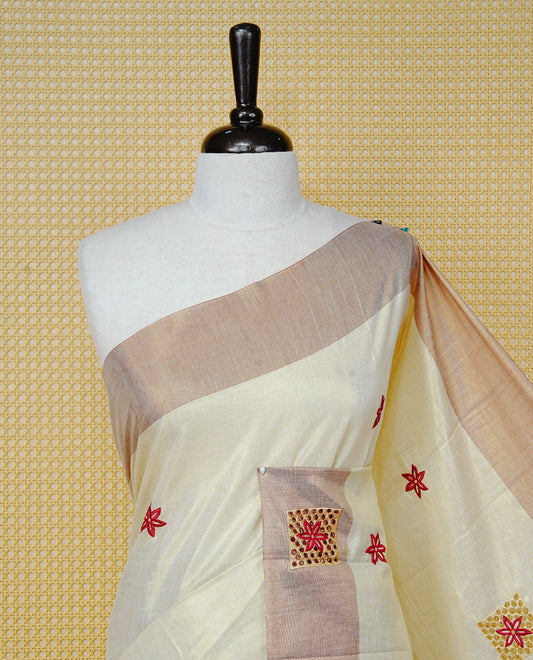 Cream Colour Tissue Kerala Saree Featuring Delicate Brick Red Floral Embroidery Work Across The Body, Enhanced With A Light Brown Zari Border And A Rich Brick Red & Gold Zari Pallu, Finished With Brick Red Tassels And A Matching Blouse Piece