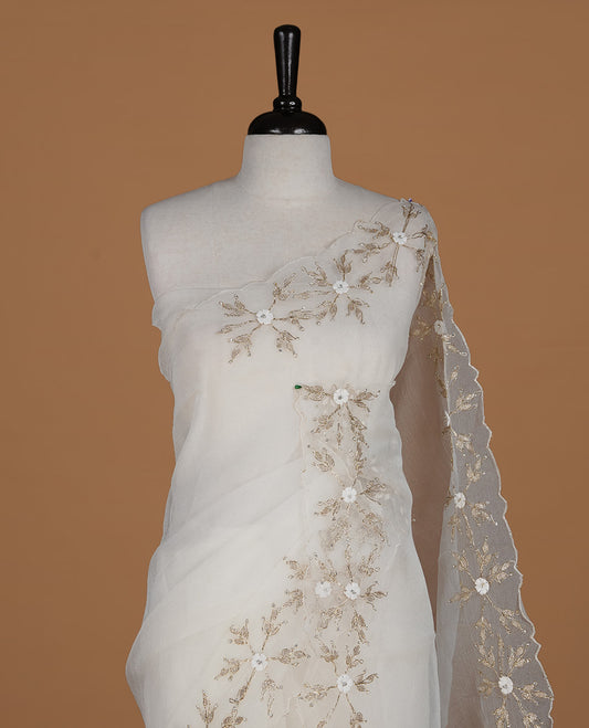 White colour crush organza saree featuring gold threan floral and stone worked body, highlighting scalp designed border, paired with matching blouse piece.