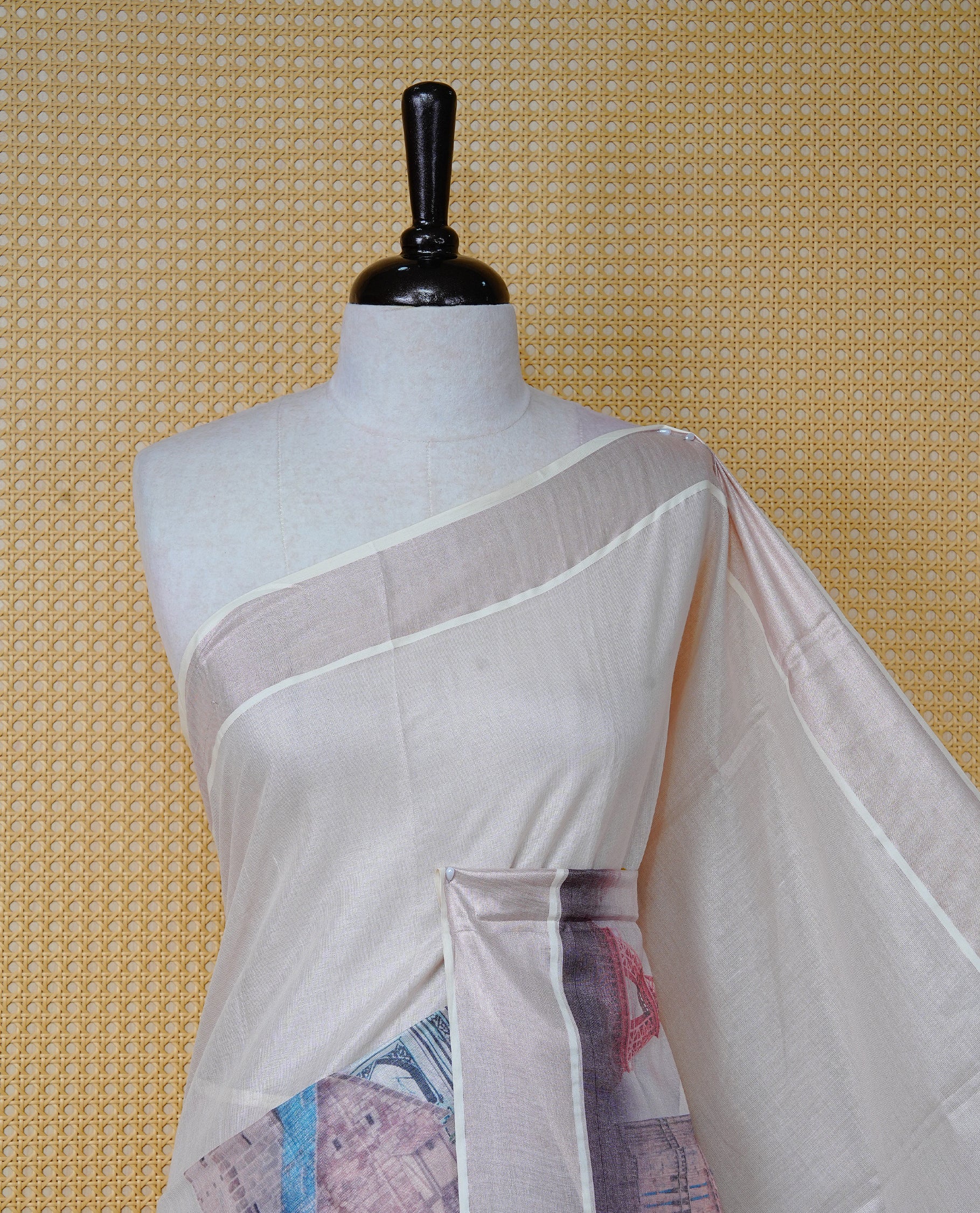 Cream colour tissue Kerala Saree featuring a clean plain body with painted style digital prints of Seven Wonders, rose gold border, Finished with pink and black tassels, and paired with a matching blouse piece.