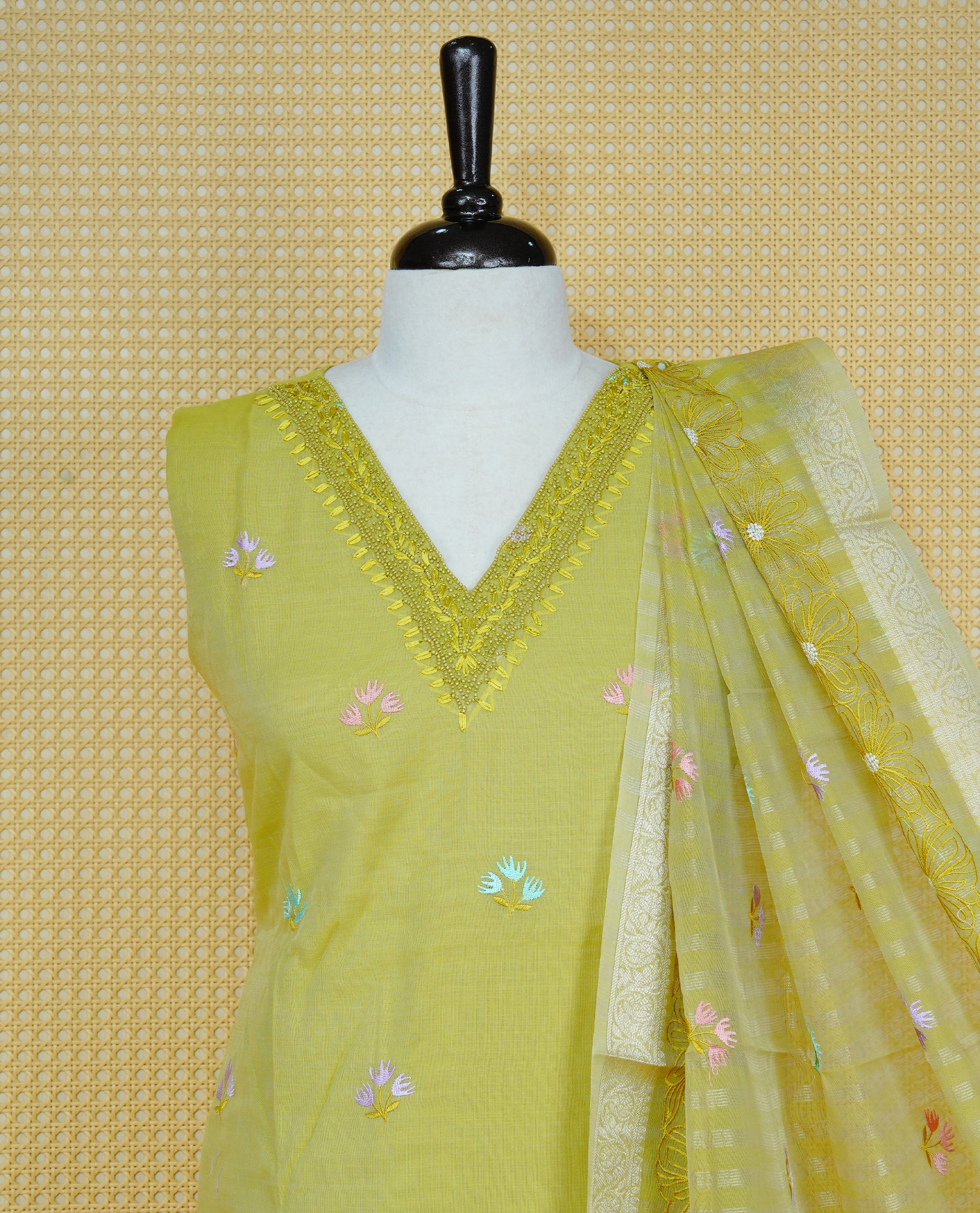 Lemon green colour churidar set with a beaded V-neckline, pastel floral buti embroidery and floral hem detailing, paired with a matching embroidered bordered dupatta and solid pants.