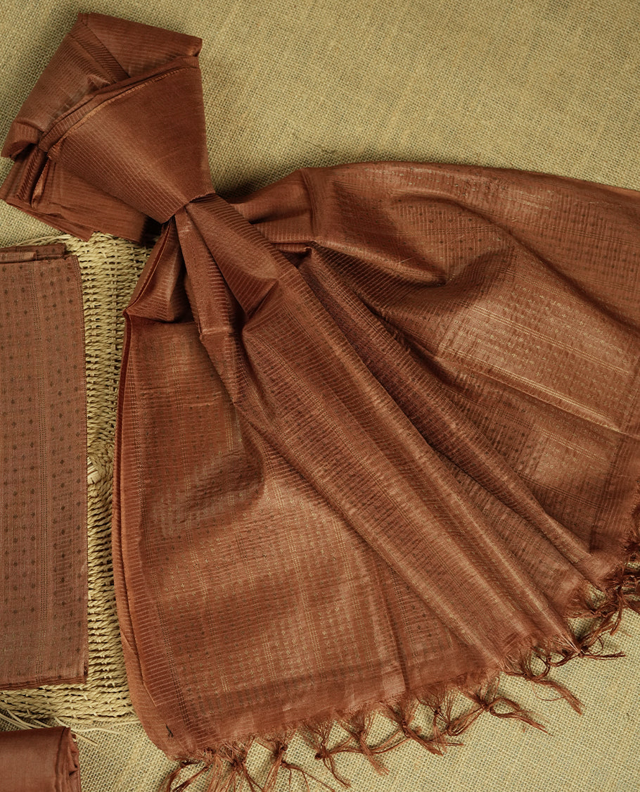 Deep brown colour tussar suit material featuring a subtle self copper zari woven motifs and vertical and stripped pattern on the body, paired with a lightweight matching dupatta with tassel edges and a plain bottom piece.