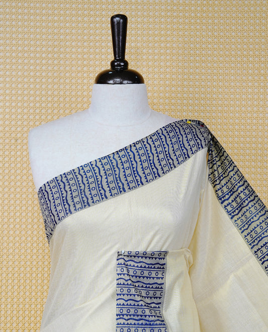 Cream Colour Tissue Kerala Saree Featuring Blue Geometric Digital Prints Along the Border, Enhanced with a Royal Blue and Gold Zari Border, Traditional Printed Pallu, Finished with Blue Tassels and a Matching Blouse Piece