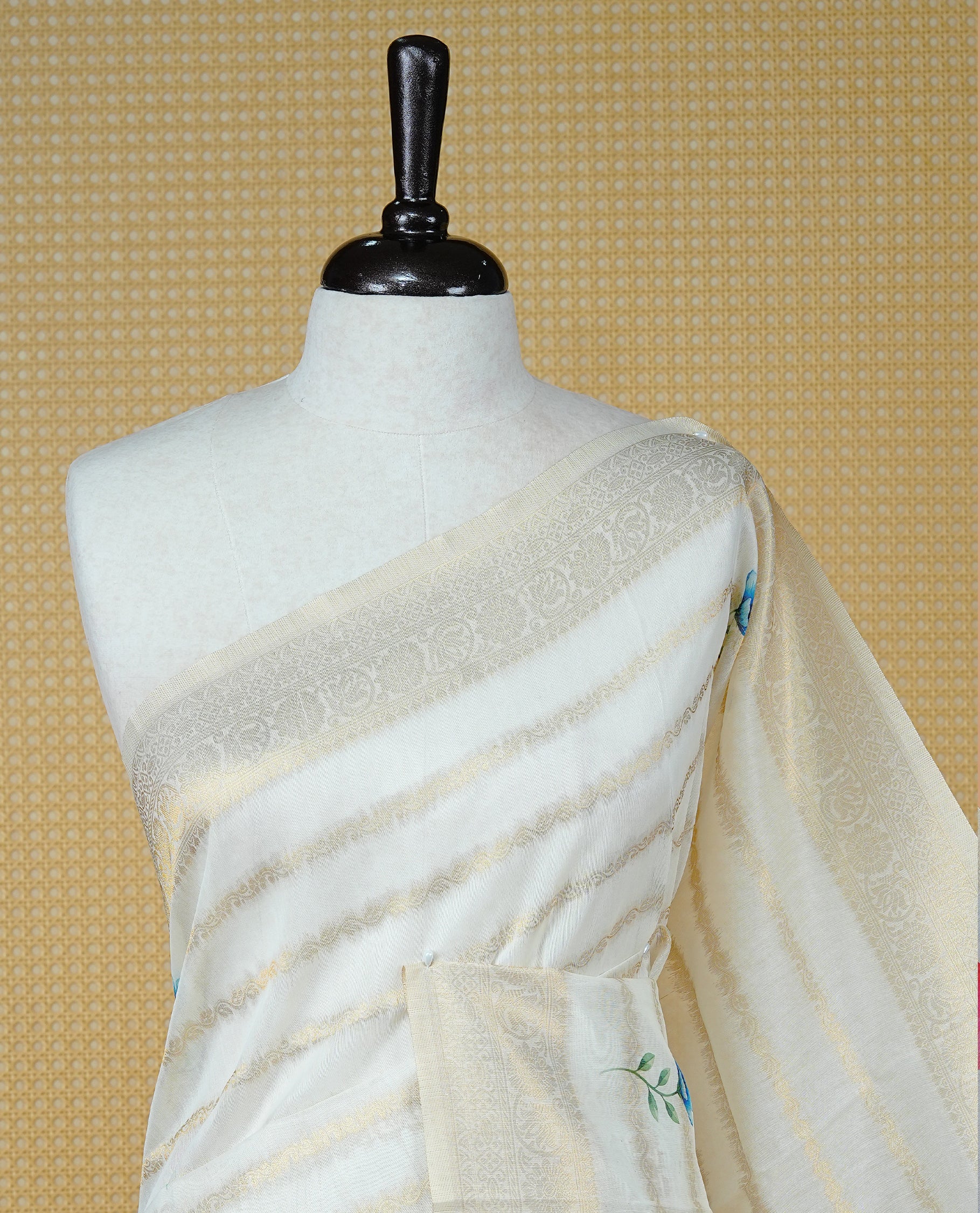 Cream Colour Organza Kerala Saree Featuring Gold Zari Strips with Floral Printed Motifs  On The Body,Paired With A Matching Blouse Piece.