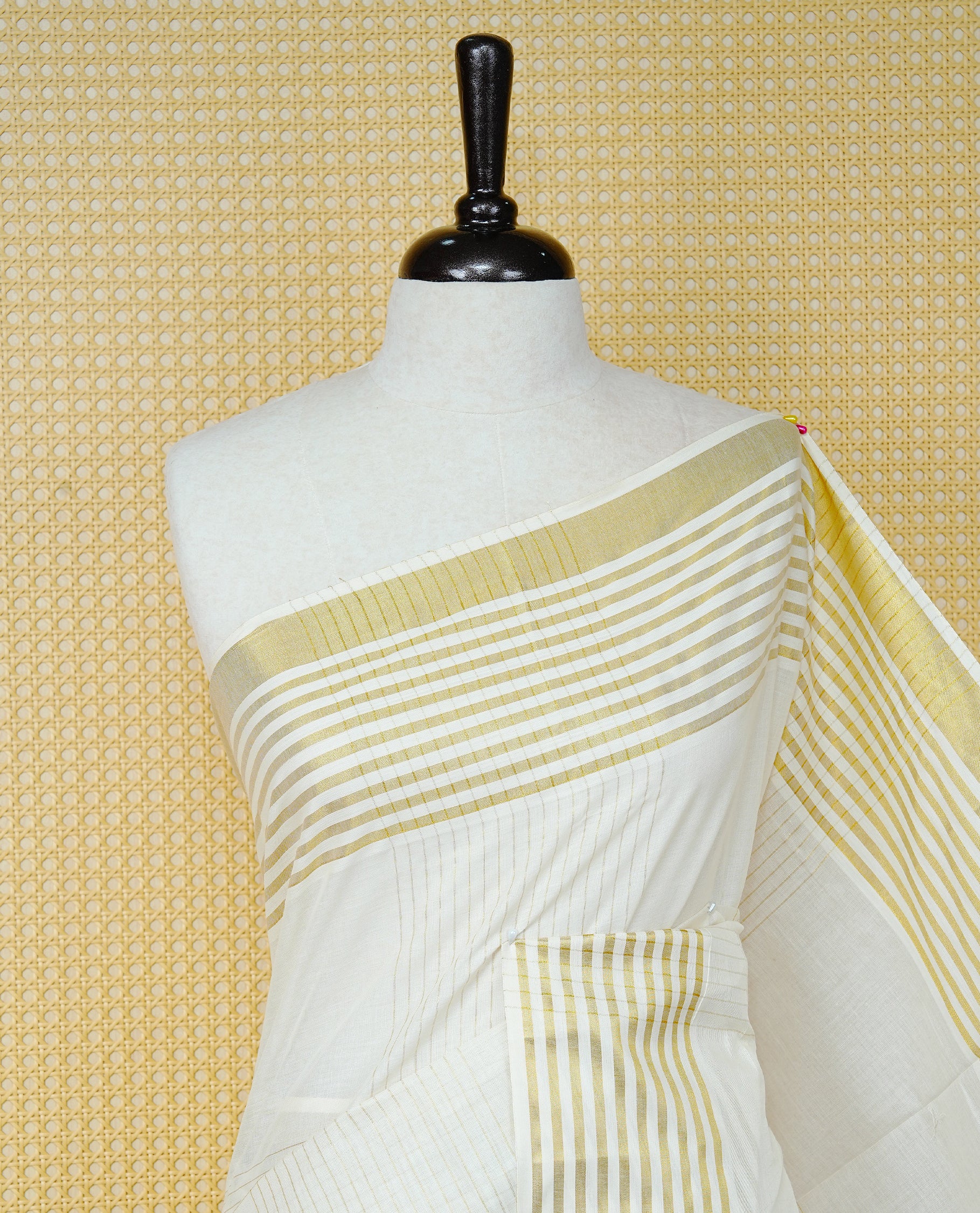 Cream Colur Cotton Kerala Saree Featuring Gold Zari Strips Across On The Body, Classic  Gold Zari Border & Pallu,Paired With A Matchinf Blouse Piece.