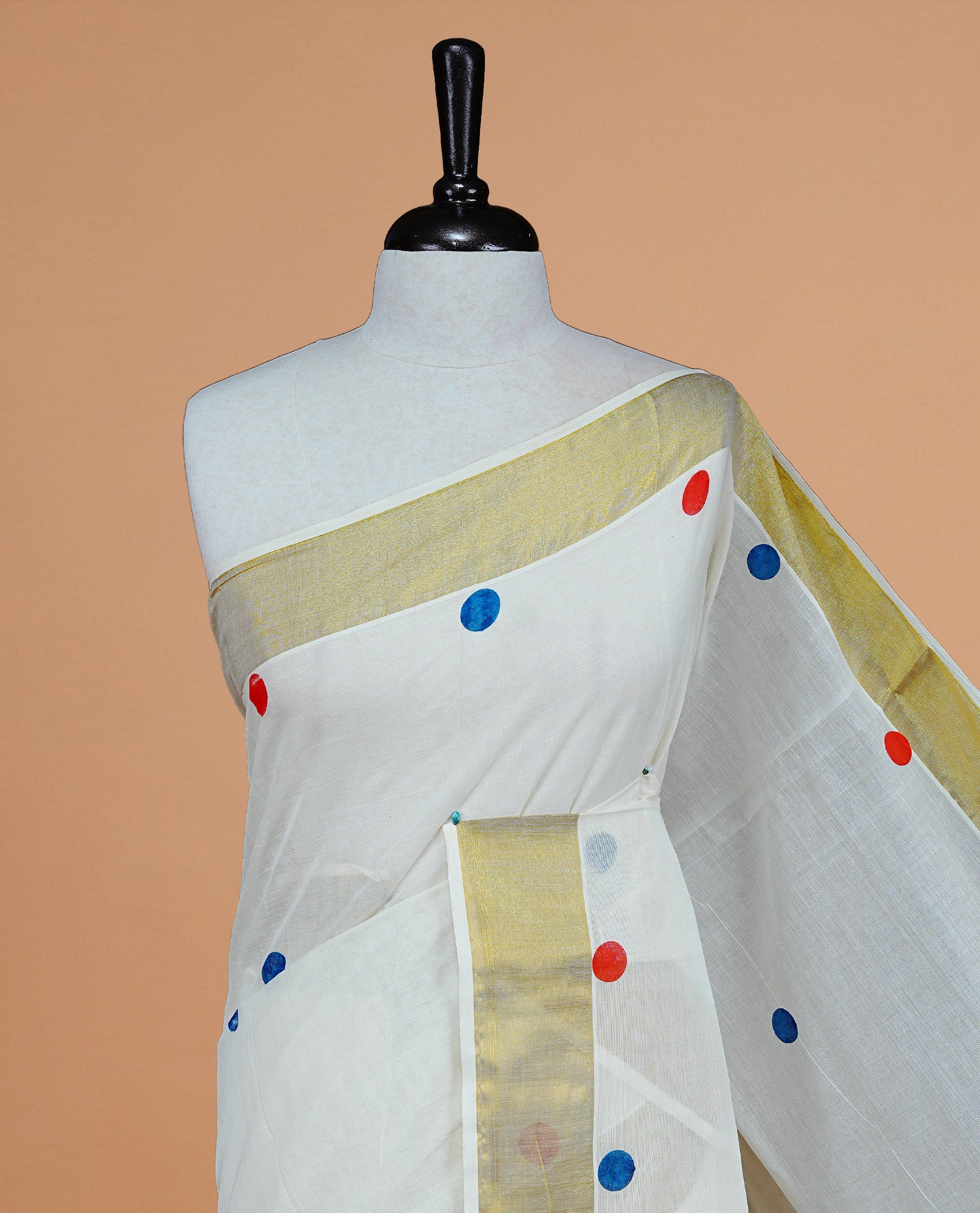 Cream Colour cotton Kerala Saree Featuring Multicolour Dot Prints On The Body, Complemented By A Traditional Gold Zari Border, Paired With A Matching Blouse Piece.